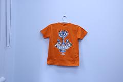 QNC - Kid's T-Shirt Short Sleeve Orange - Quadrennial Kid’s T-Shirt Short Sleeve OrangeArt by Reg Mombassa